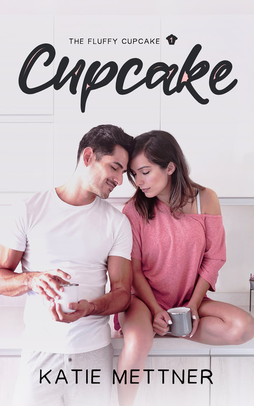 The top of the cover says The Fluffy Cupcake 1 Cupcake. There is a woman sitting on the counter in a pink shirt holding a coffee cup. her legs are bare. There is a man next to her in a white t-shirt and boxers holding a cup of coffee. They have their foreheads touching. At the bottom it says, "Katie Mettner"