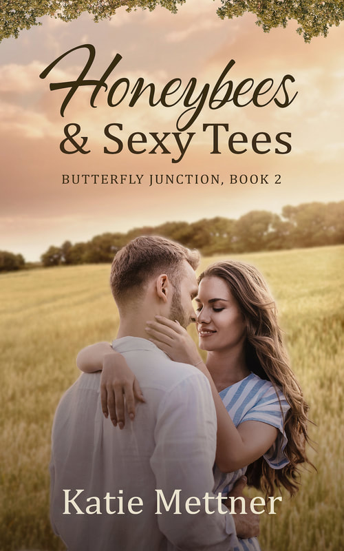 The background is a summer wheatfield with a cloudy sky at sunset. There is a couple at the bottom of the cover. She is wearing a blue and white striped dress and he is wearing a white shirt. She has long brown hair and has her hand on his face. The top says, Honeybees and Sexy Tees. Butterfly Junctoin Book 2. Katie Mettner
